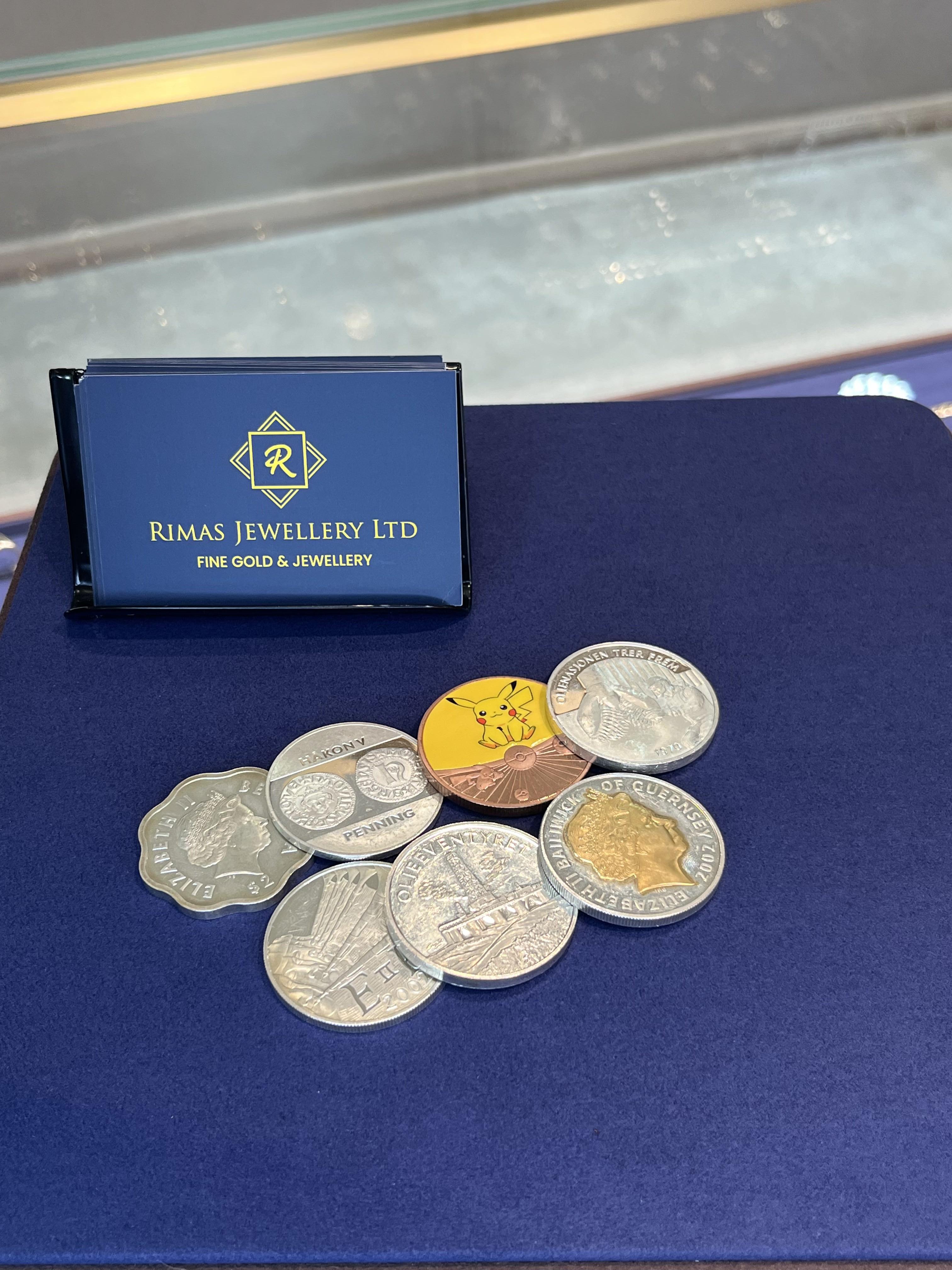 Silver coins on navy velvet beside a stand of Rimas Jewellery business cards.