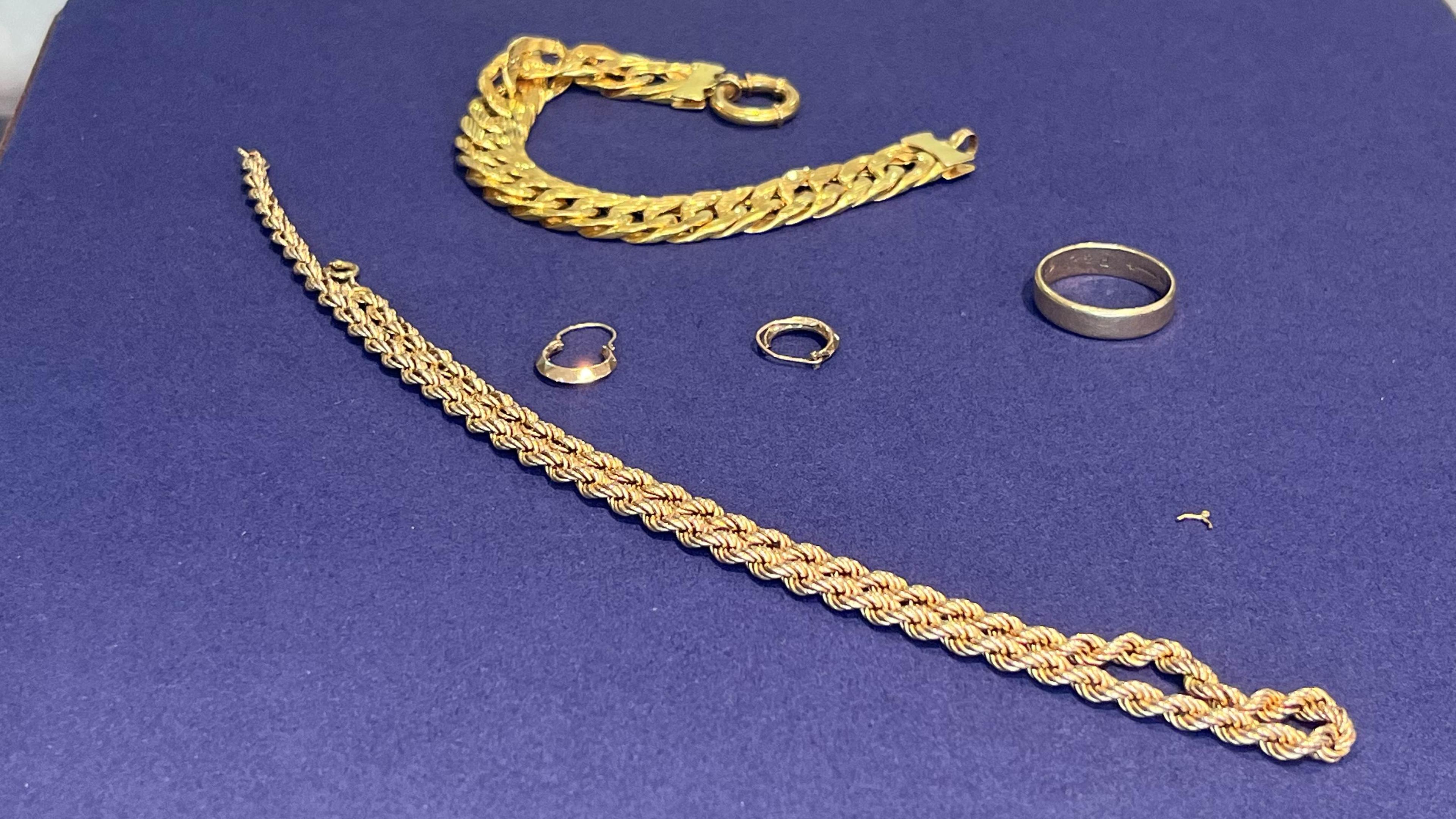 Assorted gold jewellery and scrap on a dark surface, ready to be weighed.