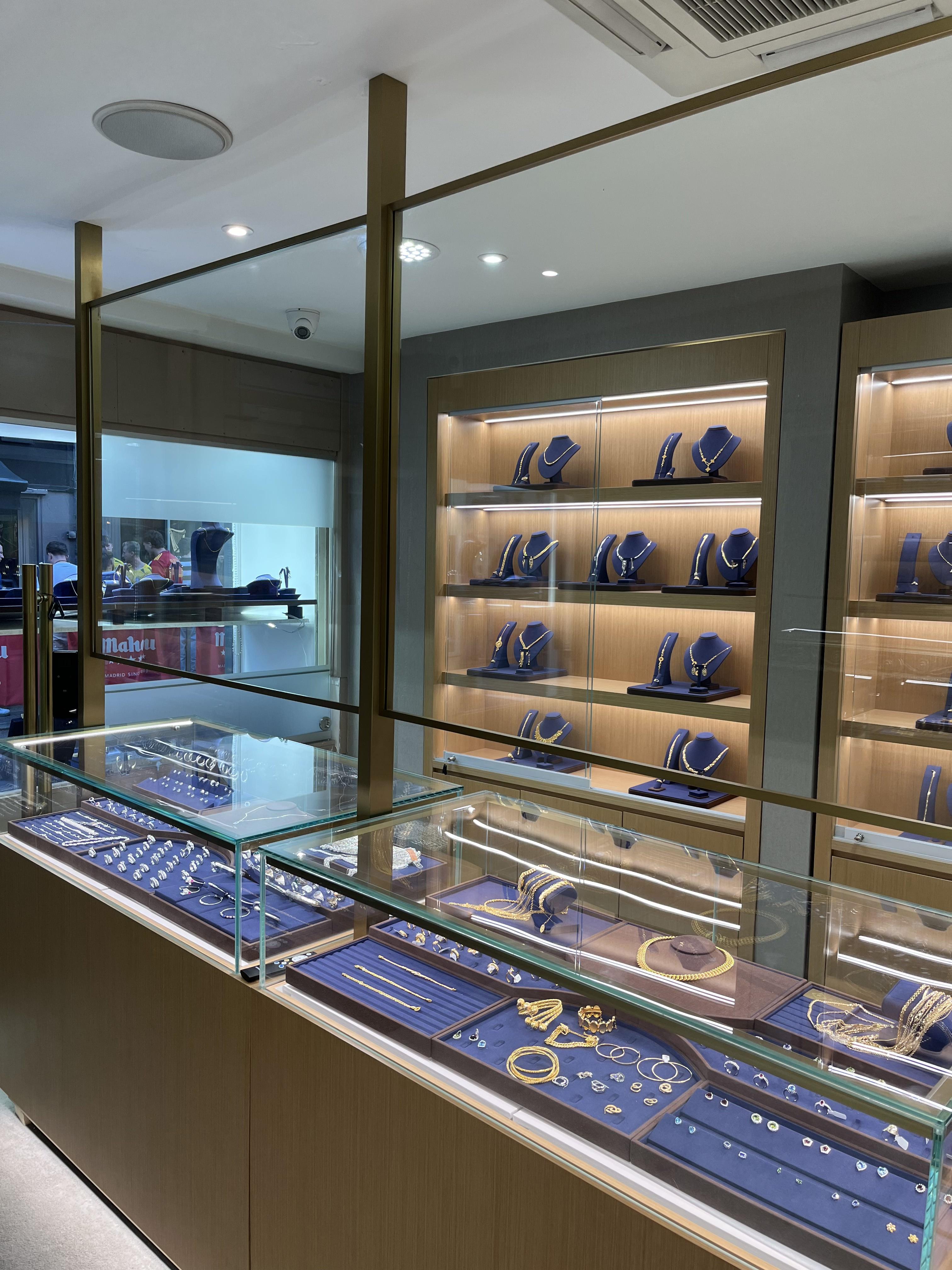 Inside Rimas Jewellery: glass counters of gold and silver jewellery in front of lit display cabinets.