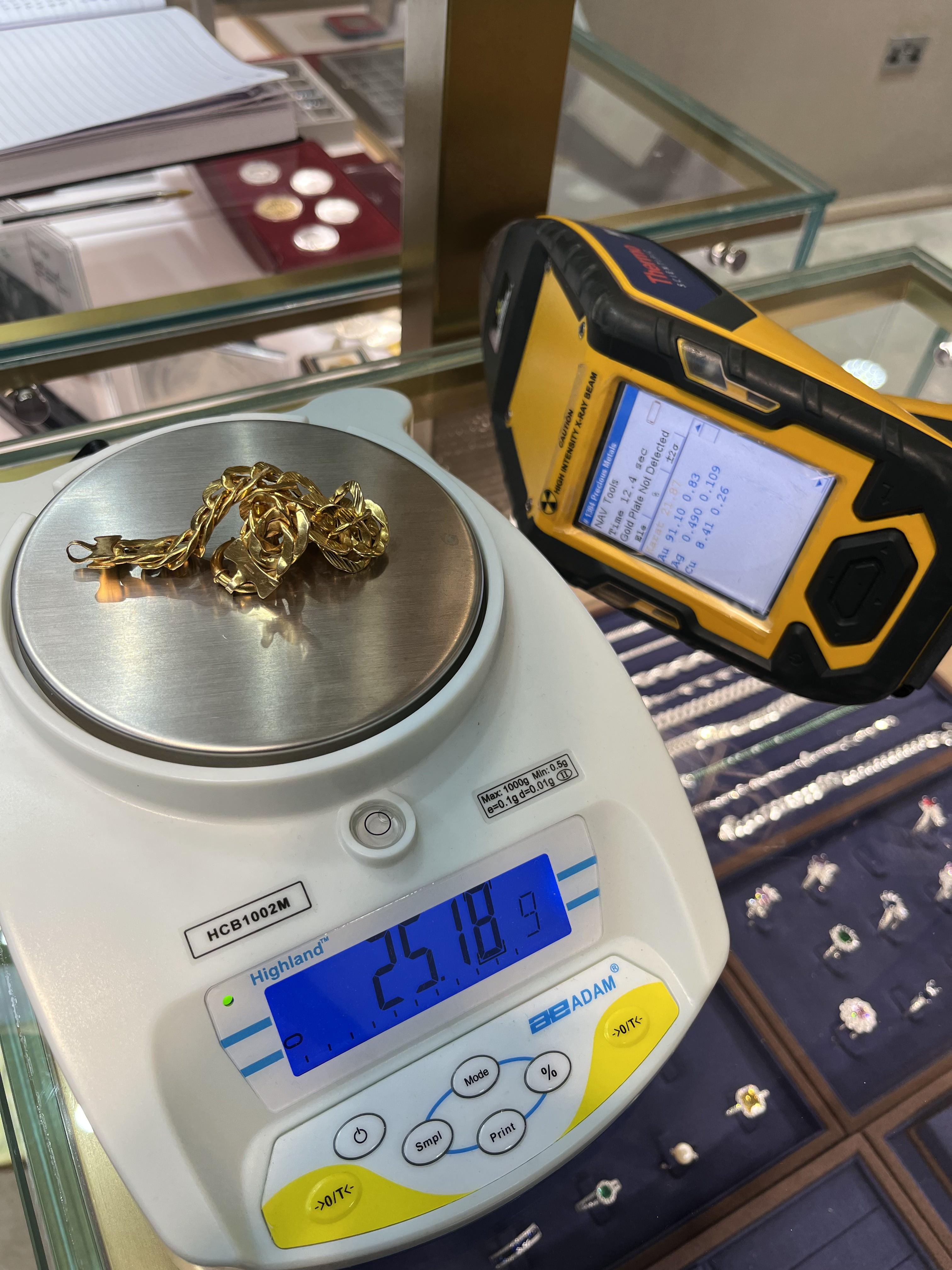 A gold chain on precision scales at the counter, with the XRF analyser reading beside it.